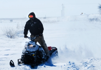 Joel Nelson rides his snow mobile through snow drifts on County road 17 Sunday afternoon. Many county roads were impassable Sunday afternoon due to blowing and drifting snow. Snow cleanup in W. County